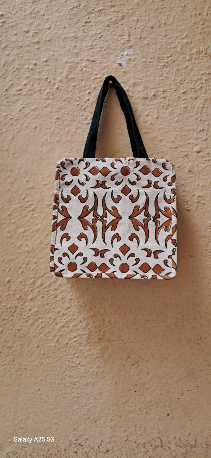Mini handbag in a brown and white ikat-style block print with black handles