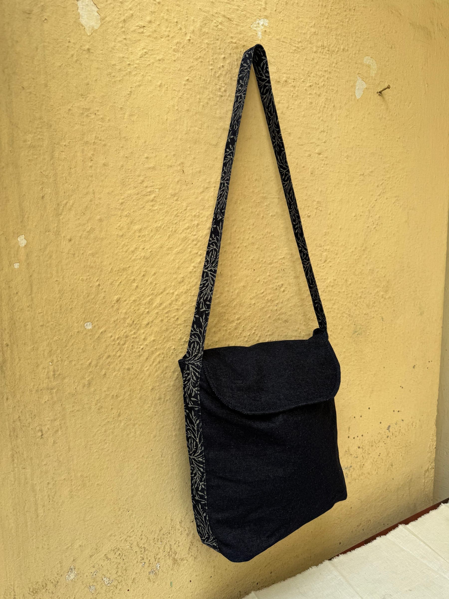 Black cotton sling bag with a flap and a block-printed shoulder strap