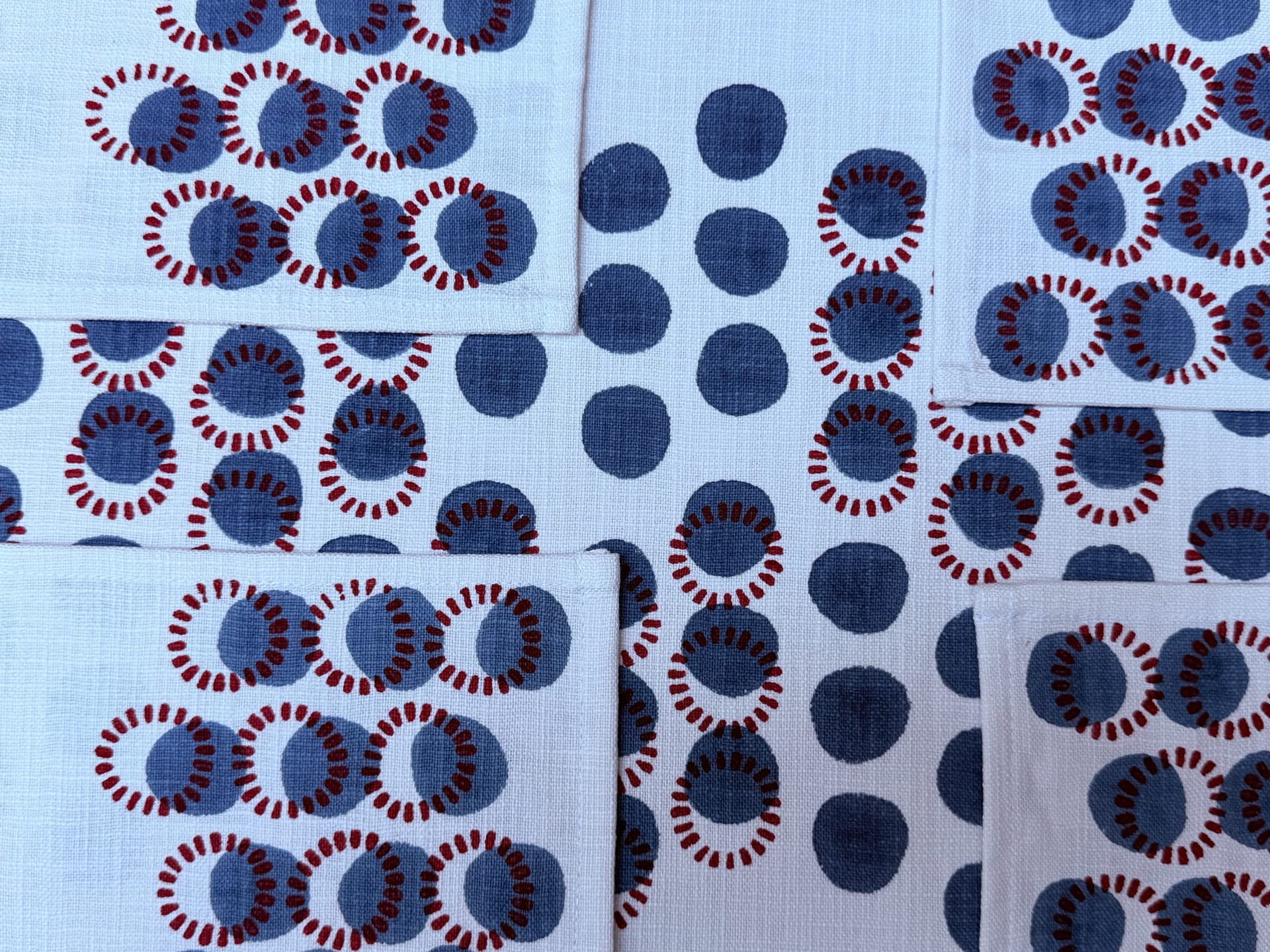 Finished napkins block-printed with indigo dots and rust ring motifs, laid edge to edge