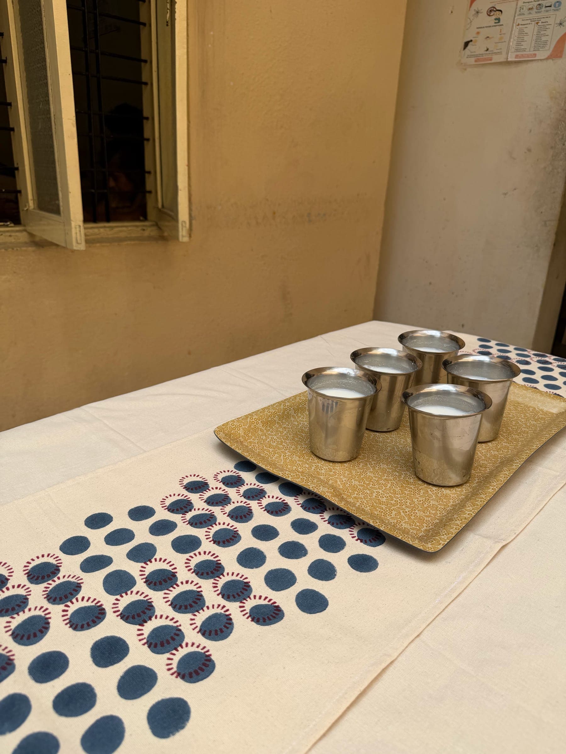 Steel tumblers on a tray sit on a freshly printed indigo-dot table runner at the studio