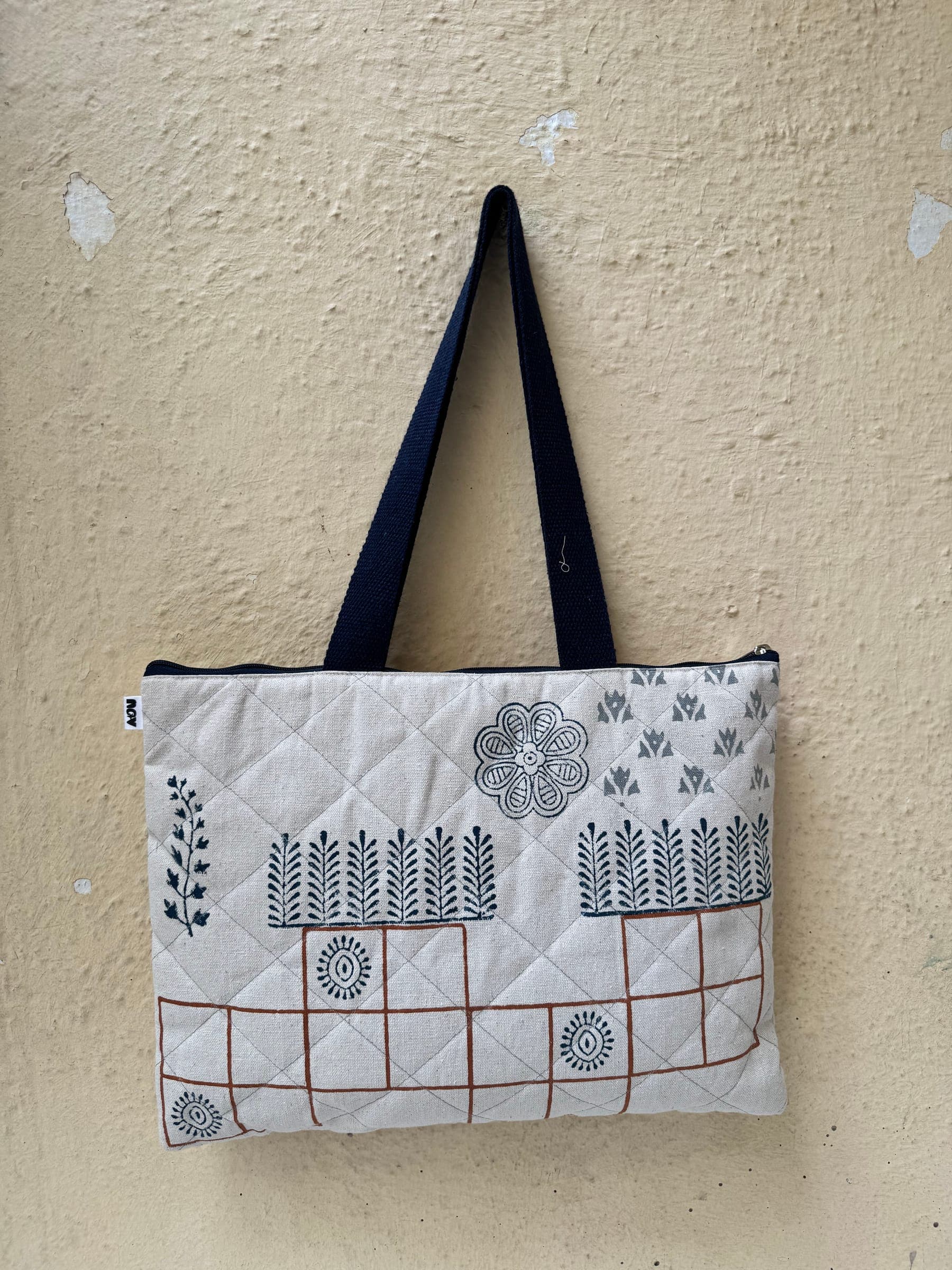 Quilted zip tote block-printed with a garden of ferns, flowers and a terracotta grid, navy canvas handles