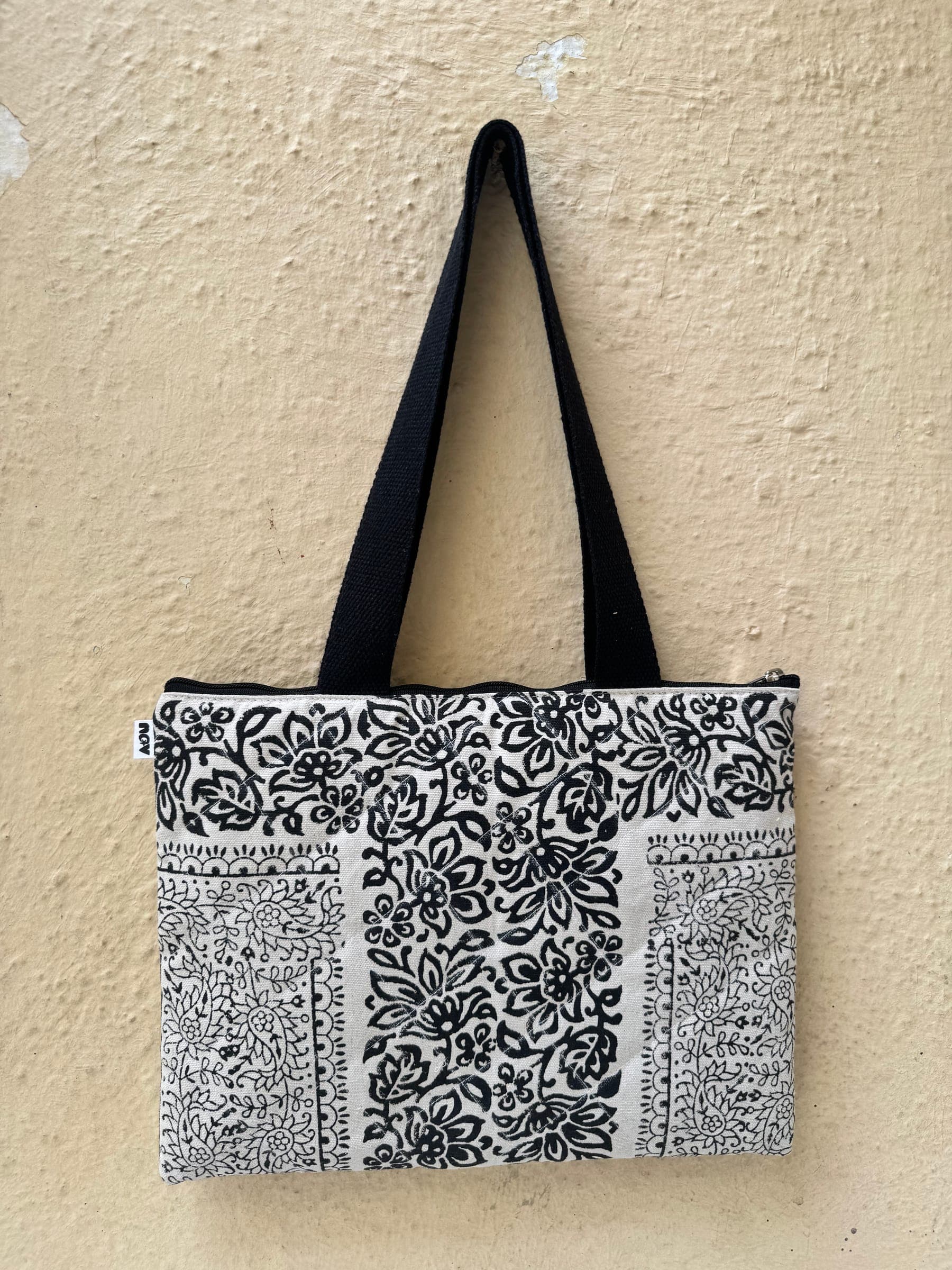 Quilted zip tote in black and white floral block prints arranged as a patchwork, black handles
