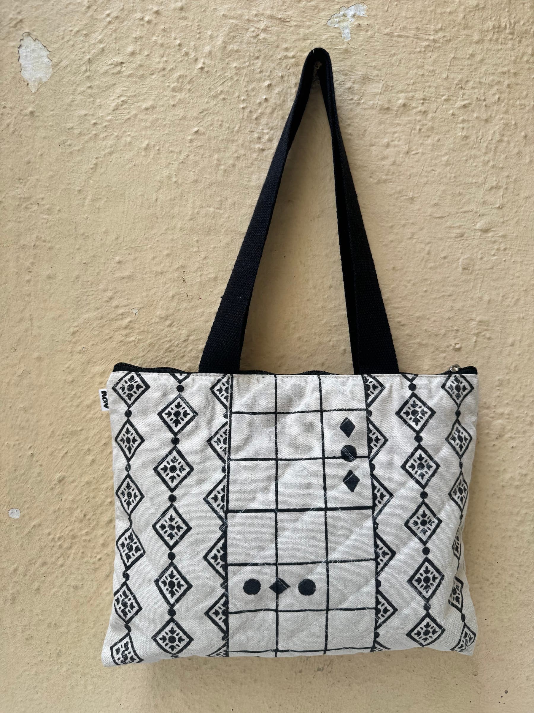 Quilted zip tote with black geometric diamond and grid block prints on white, black handles