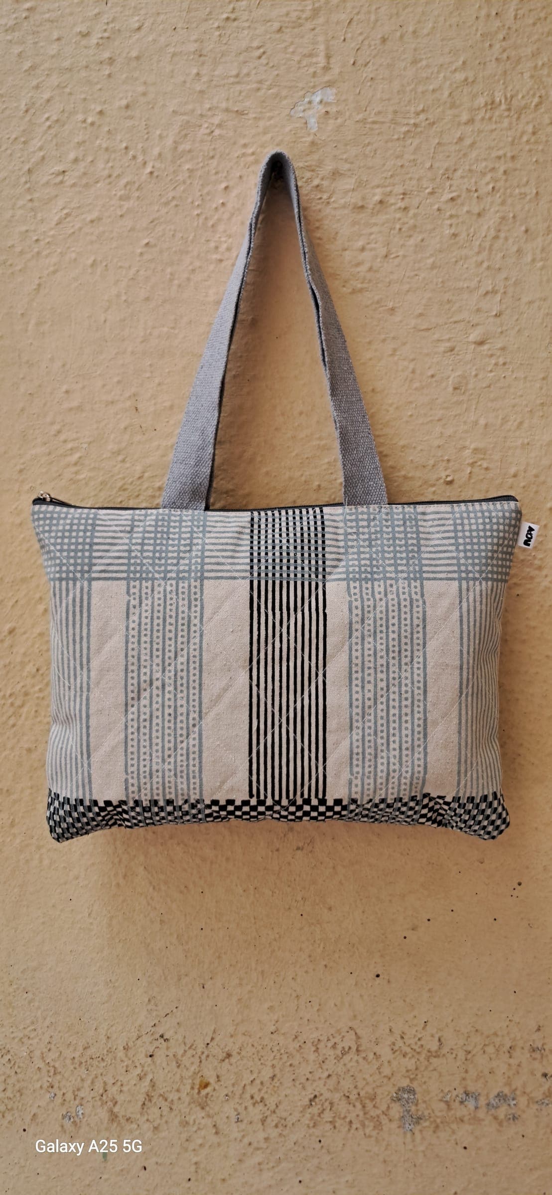 Quilted zip tote in woven grey stripes with a dotted border, grey canvas handle