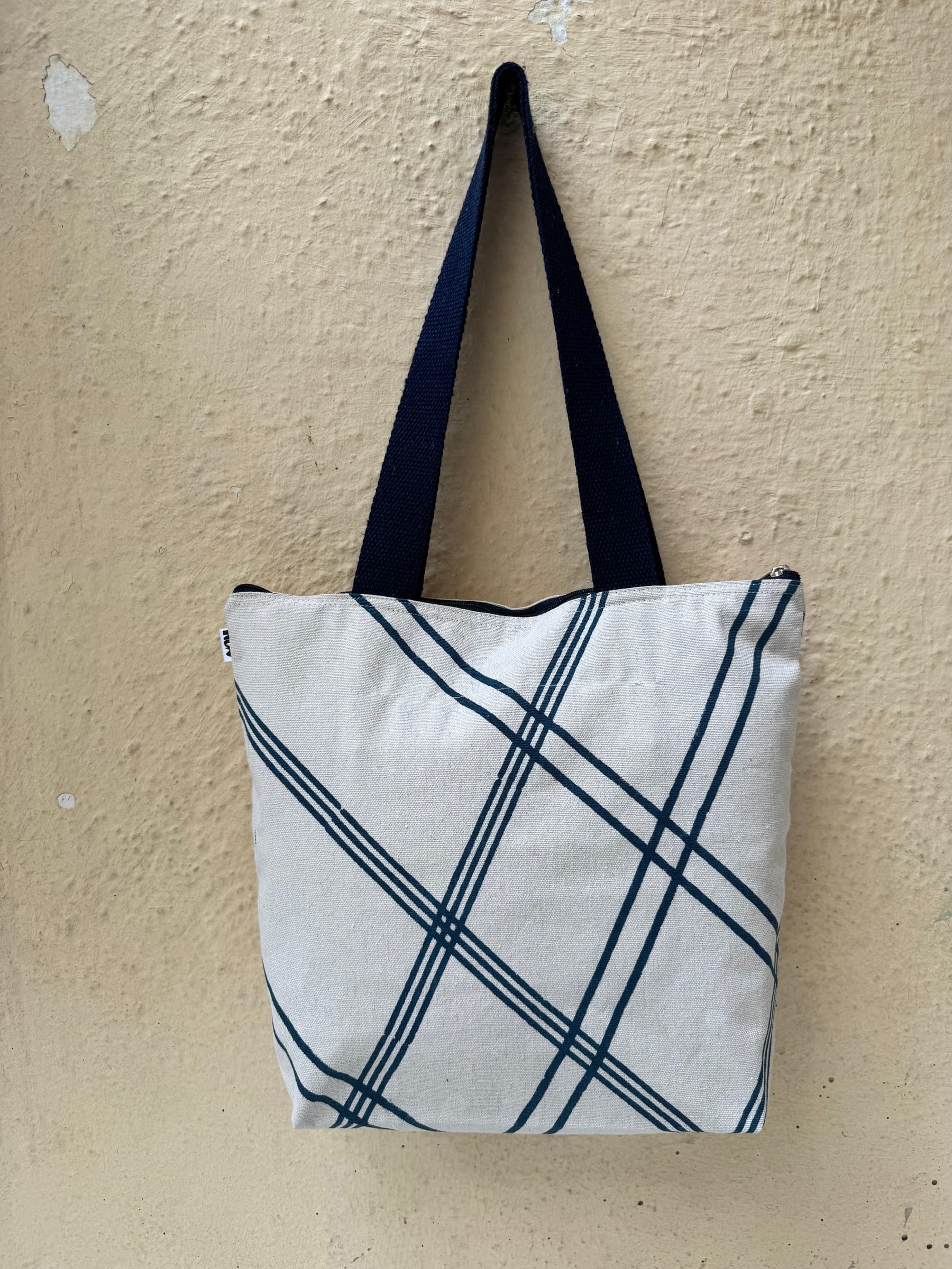Cotton tote block-printed with a navy diagonal windowpane grid, navy handles