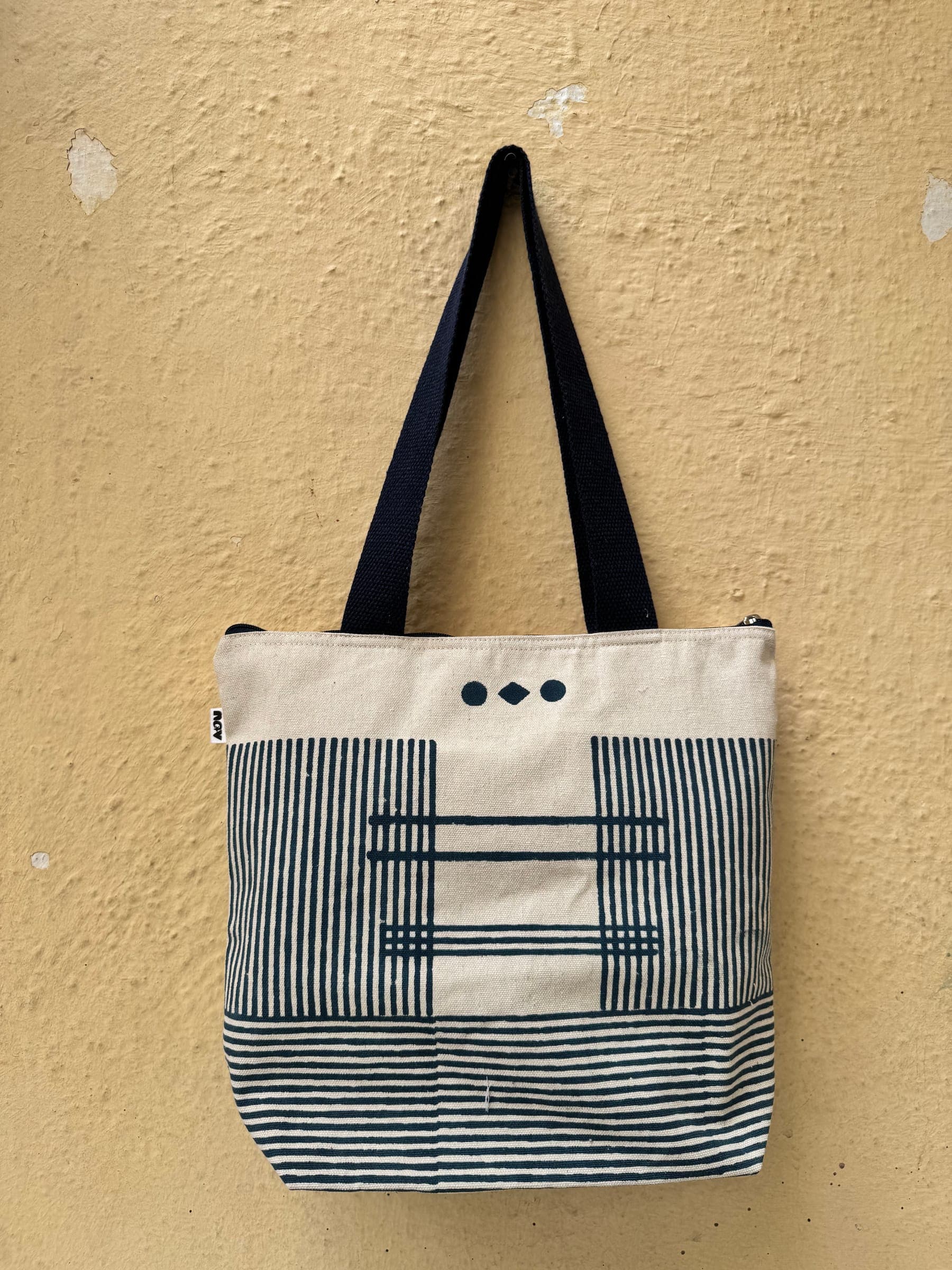 Cotton tote with a navy stripe panel and three hand-printed dots on cream, navy handles