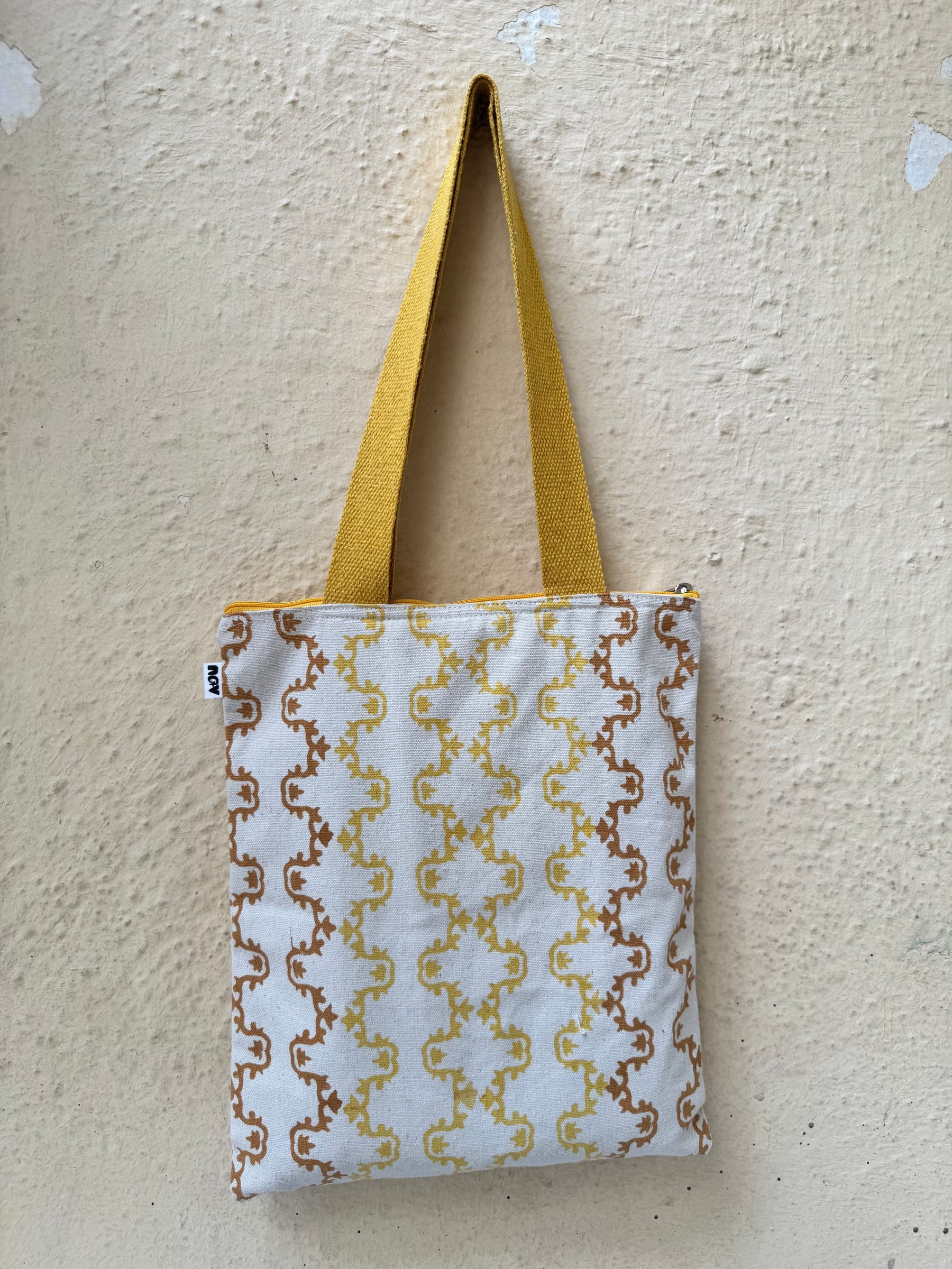 Cotton tote in a gold and brown chain-link block print with mustard handles