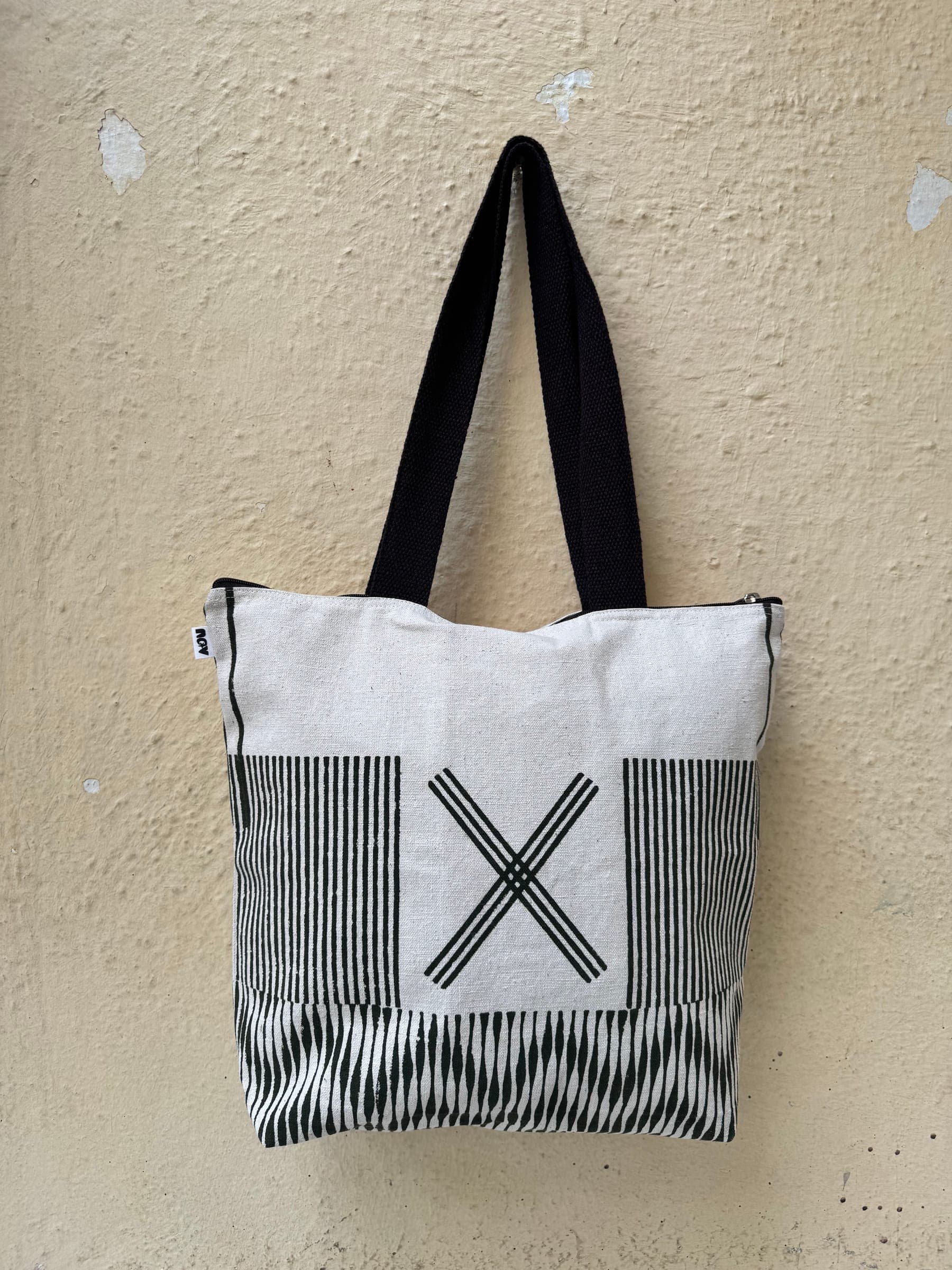 Cotton tote with a bold printed X motif on cream over stripe and zigzag panels, black handles