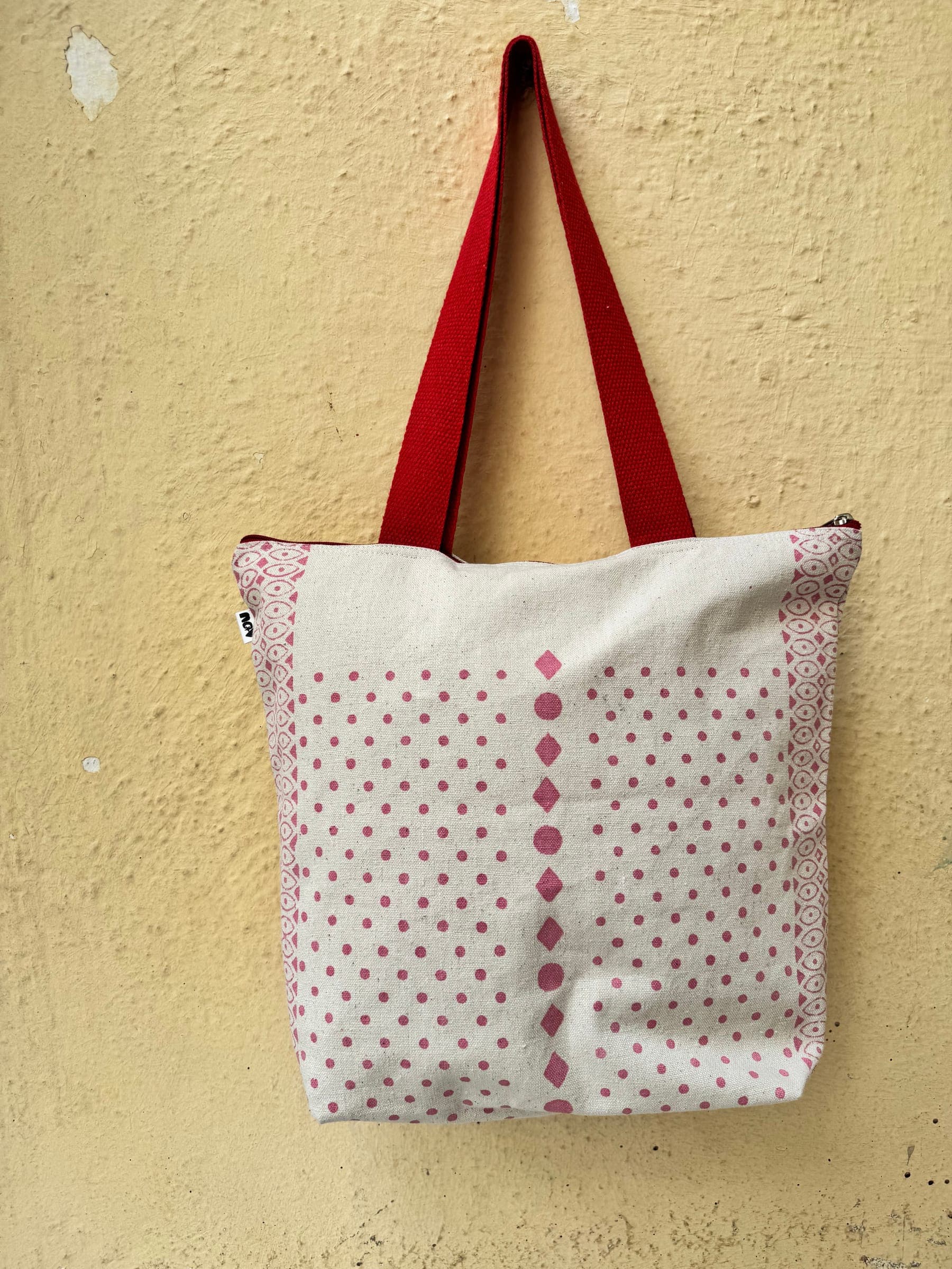Cotton tote with rows of red diamond dots block-printed on cream, red handles
