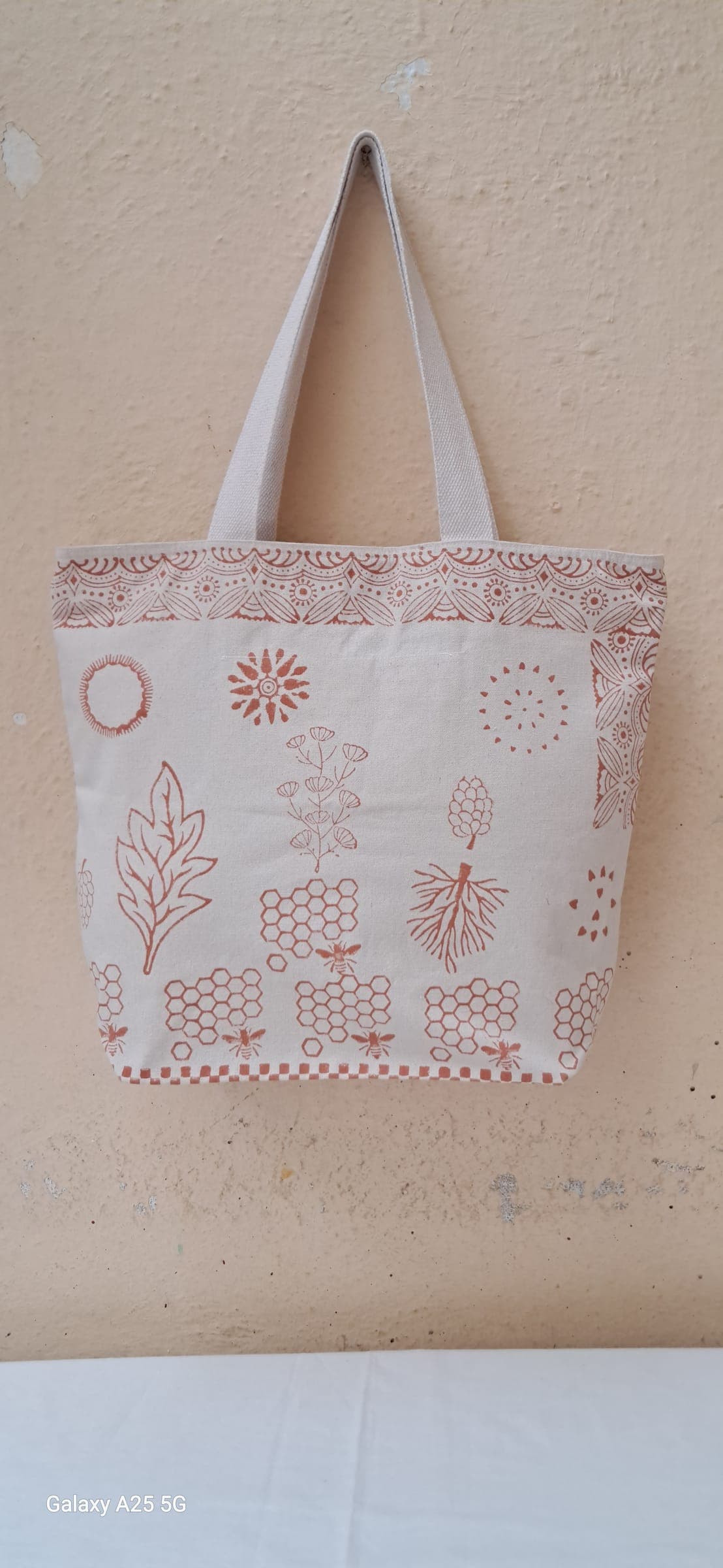 Cotton tote hand-printed in rust with a sampler of suns, ferns and honeycomb motifs