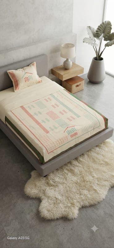Single bedspread in cream with pastel block motifs and a matching pillow, styled on a bed